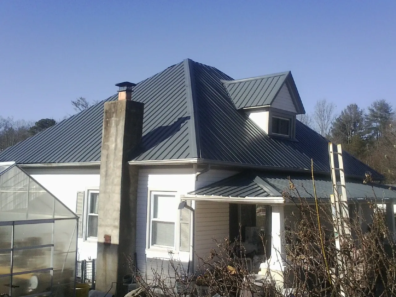 Dark blue standing seam metal roof on a white farmhouse with dormer — Slate & Tile Roof Repair by Roofing Brothers in Athens